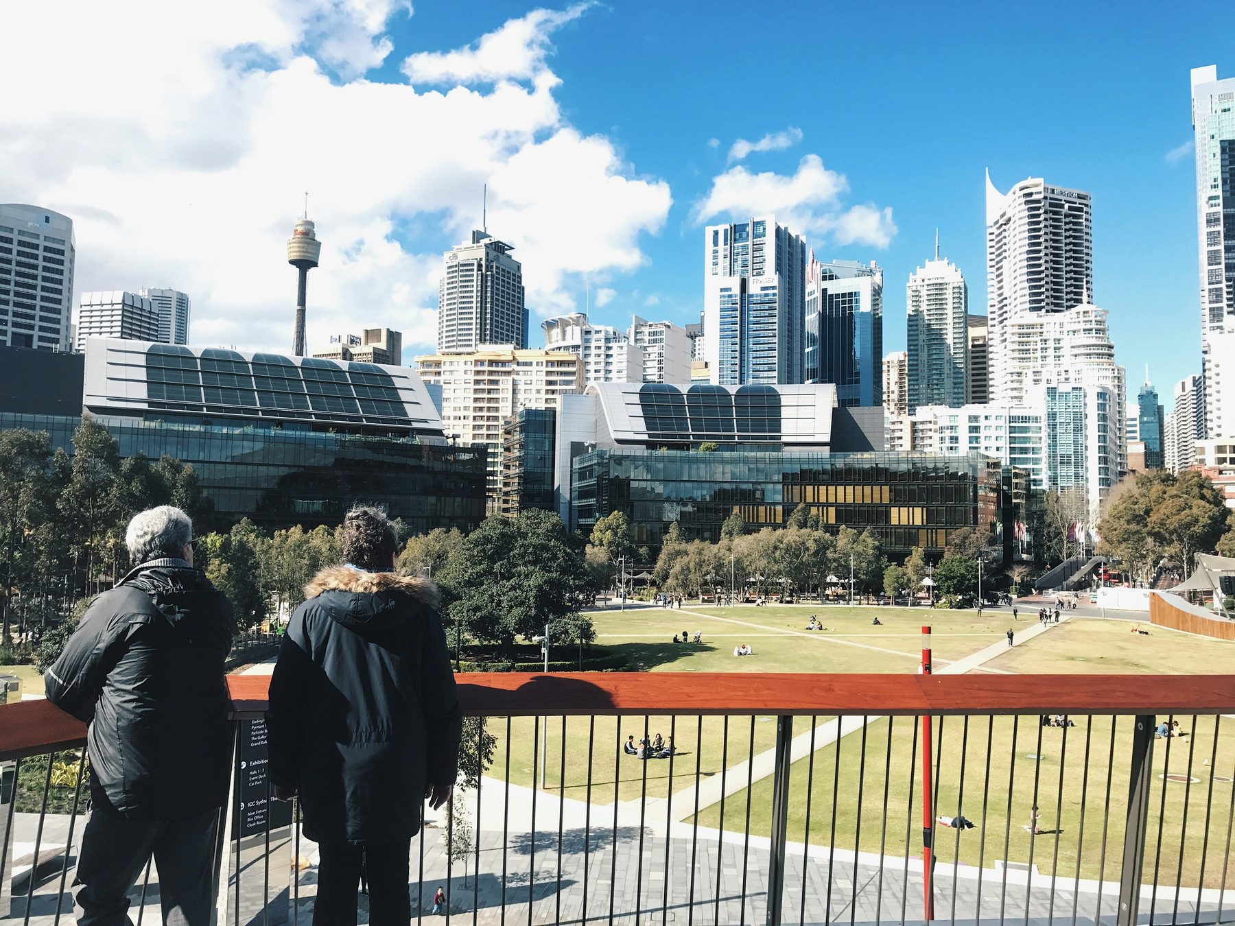 Two people looking out over the Sydney CBD skyline from Darling Harbour on a clear day