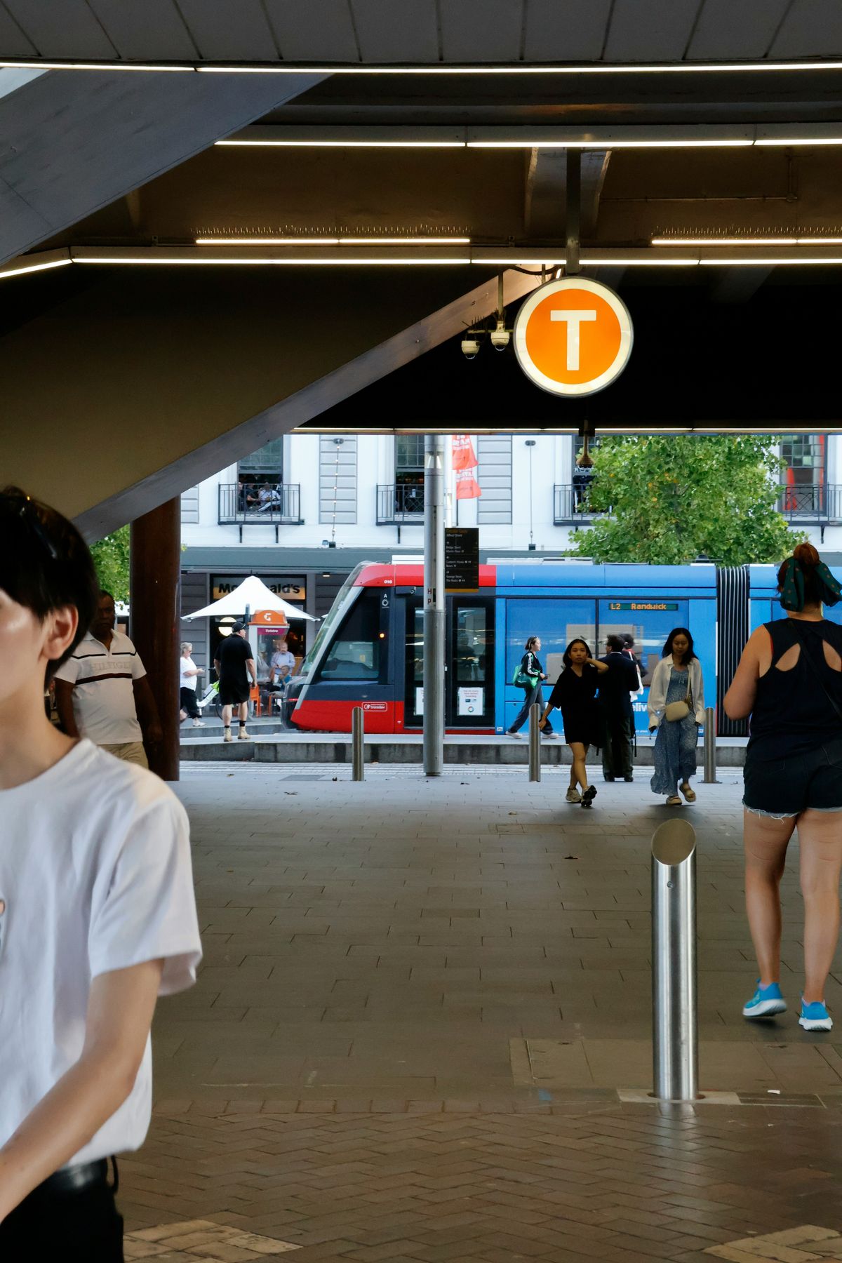 Sydney light rail station with tram and commuters